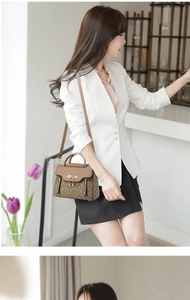 Chic women's crossbody bag with pearl tassel and metal handle on a white suit model