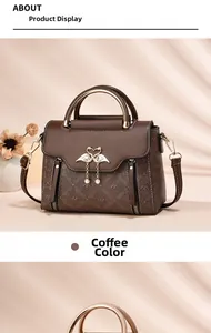 Detail view of coffee leather handbag featuring golden swan clasp and pearl tassel charm