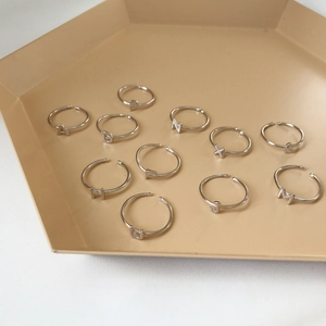 Minimalist handcrafted 925 sterling silver alphabet letter rings on a beige tray