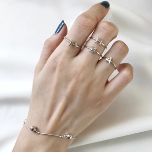 Close-up of S925 sterling silver letter rings and bead bracelet on silk fabric