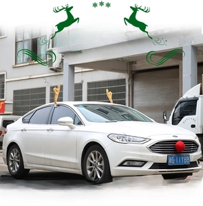 Detailed view of plush reindeer antlers with red bows and nose on a white car exterior