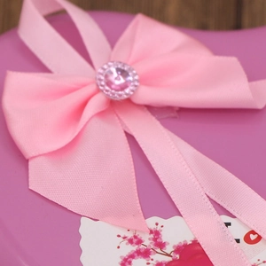 Close-up of pink heart-shaped gift box with satin ribbon bow and I love you card