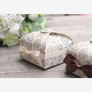 Macro shot of two vintage floral paper gift boxes with elegant beige and brown ribbon bows