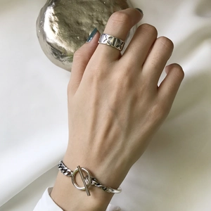 Detail of silver chain bracelet with T-bar clasp and engraved ring on hand model