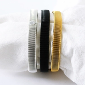Detailed set of silver, black and gold metal spring armbands on white fabric display