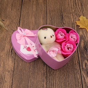 Macro view of heart-shaped pink tin box with plush bear and soap roses on wood surface