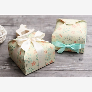 Close-up of vintage floral paper gift boxes with elegant white and mint green ribbons