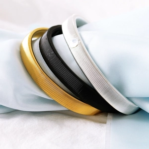 Detailed view of silver, gold and black metal spring armbands on fabric background