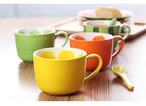 Detail of fruit-themed ceramic mugs showing interior fruit patterns with matching spoons