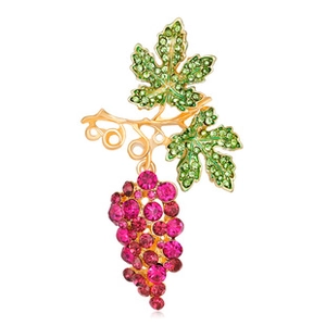 Detail view of a grape brooch with pink crystals and green leaves on gold metal