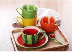 Detailed view of creative ceramic mugs and plates with watermelon and orange fruit designs