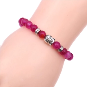 Macro detail of handmade rose red agate beaded bracelet with vintage silver Buddha charm