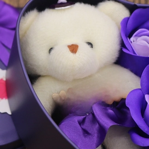 Detail of white plush bear and purple soap roses in a heart-shaped gift box set
