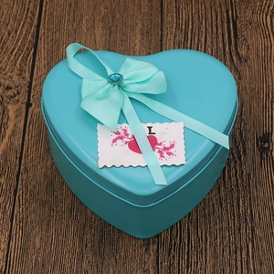 Blue heart-shaped metal gift box with a silk ribbon bow and Love greeting card
