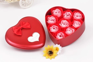 Detailed view of 9 pink soap roses inside a red heart-shaped metal gift box with ribbon