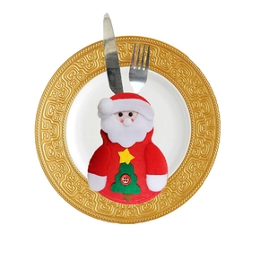 Close-up of Santa cutlery holder on a gold-rimmed white plate with metal fork and knife
