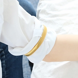 Close-up of golden metal spring sleeve garter holding a white shirt cuff in place