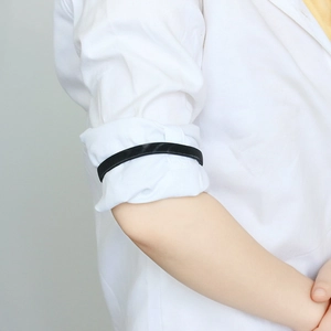 Detail of a black metal elastic shirt sleeve garter worn on a white dress shirt arm
