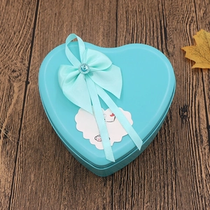 Close-up of heart-shaped tin gift box with a blue ribbon bow and sparkling diamond accent