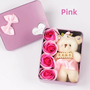 Macro shot of purple gift tin with plush bear and pink soap flower roses inside