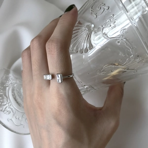 Close-up of minimalist silver ring with dual rectangular crystals worn on hand