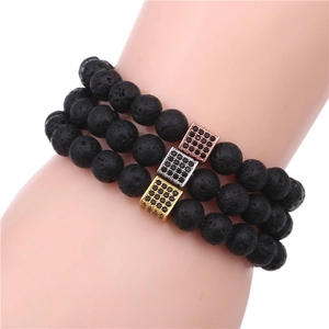 Detailed shot of three black lava stone bracelets with rose gold, silver and gold metal charms