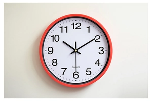 Detail of a 12-inch wall clock with red frame, black hands and white quartz dial face