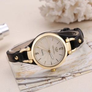 Detail view of RINNADY quartz watch with gold case and black leather strap on vintage card