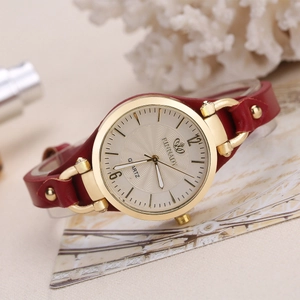 Detail of red leather strap and gold quartz watch dial on a vintage background