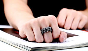 Close-up of men's punk style multi-skull ring in vintage silver on a model's hand
