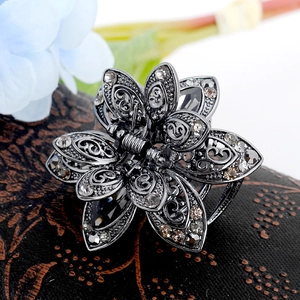 Macro view of crystal lotus hair claw clip in dark grey metal finish for women