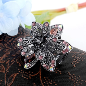 Detail view of retro flower brooch featuring pink and brown crystals on dark metal base