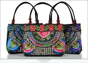 Close-up of semi-circular ethnic canvas handbags with butterfly and floral embroidery