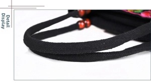 Detail of canvas handbag featuring ethnic embroidery and distinctive red bead accents