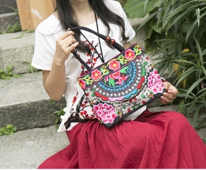 Close-up of ethnic floral embroidery and wooden beads on a canvas handbag
