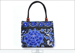 Detail of blue floral embroidery on black canvas handbag with decorative wooden beads