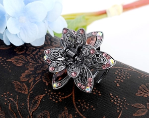 Close-up of vintage bronze flower hair claw clip with intricate pink crystals and rhinestones