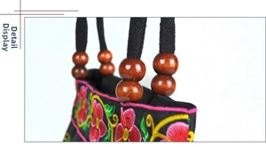 Detail of ethnic canvas handbag with vibrant floral embroidery and wooden beads