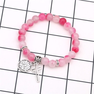 Dettaglio del bracciale con perline di agata rosa e ciondoli a croce e loto in metallo
