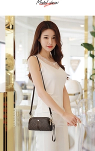 Model showing dark brown floral mini crossbody bag with golden zippers in a boutique