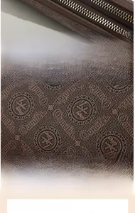 Detailed macro view of brown PU leather with embossed monogram and gold zippers