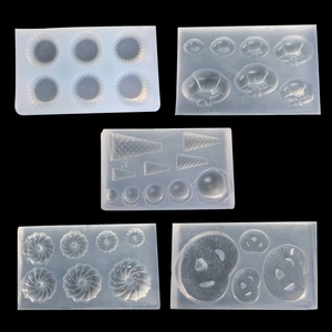 Five assorted food-grade silicone molds for mini clay donuts and croissants on black background