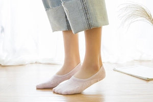 Detail of light pink low cut invisible cotton sock on foot with silicone heel grip