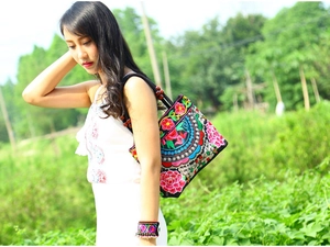 Detailed ethnic canvas bag with colorful floral embroidery and beaded wood handle