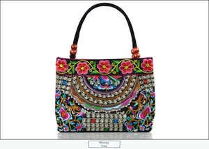 Close-up of ethnic embroidered canvas handbag with floral patterns and red wooden beads