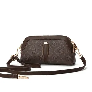 Close-up of brown crossbody bag with Qunife monogram pattern and gold metal buckle detail