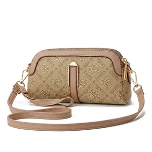 Detail view of the apricot crossbody bag with logo patterns on a marble display