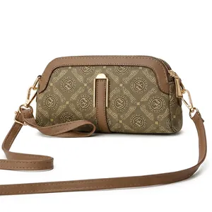 Detail of khaki crossbody bag featuring vintage canvas prints and brown leather trim