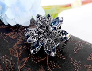 Detail of vintage flower hair claw clip with blue crystals and rhinestones in dark metal