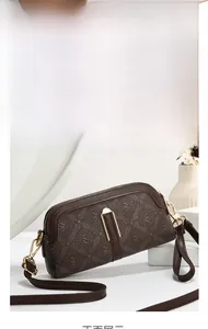 Macro shot of dark brown monogram crossbody bag with golden metal hardware and U-buckle